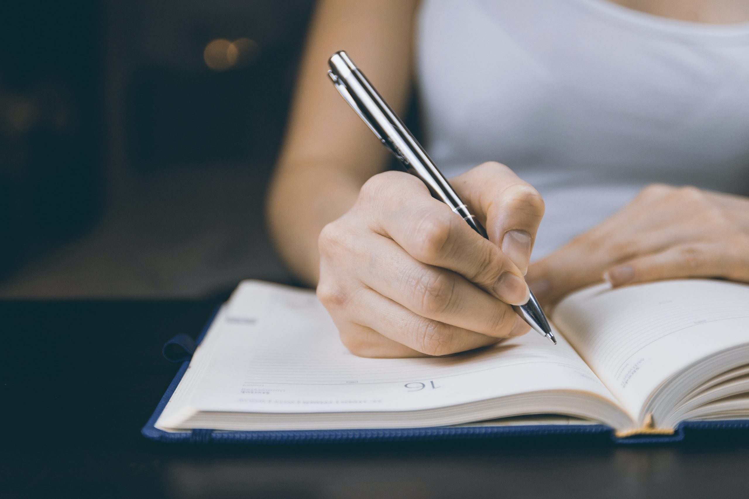 Persona escribiendo con pluma en una agenda